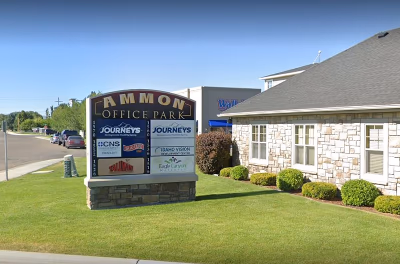 Exterior view of a stone building with a large sign and manicured lawn.