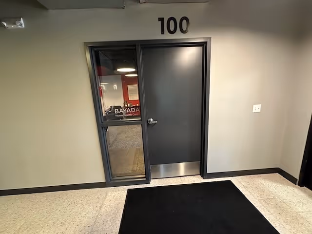 Interior hallway with a gray door labeled 100 and a glass entrance.
