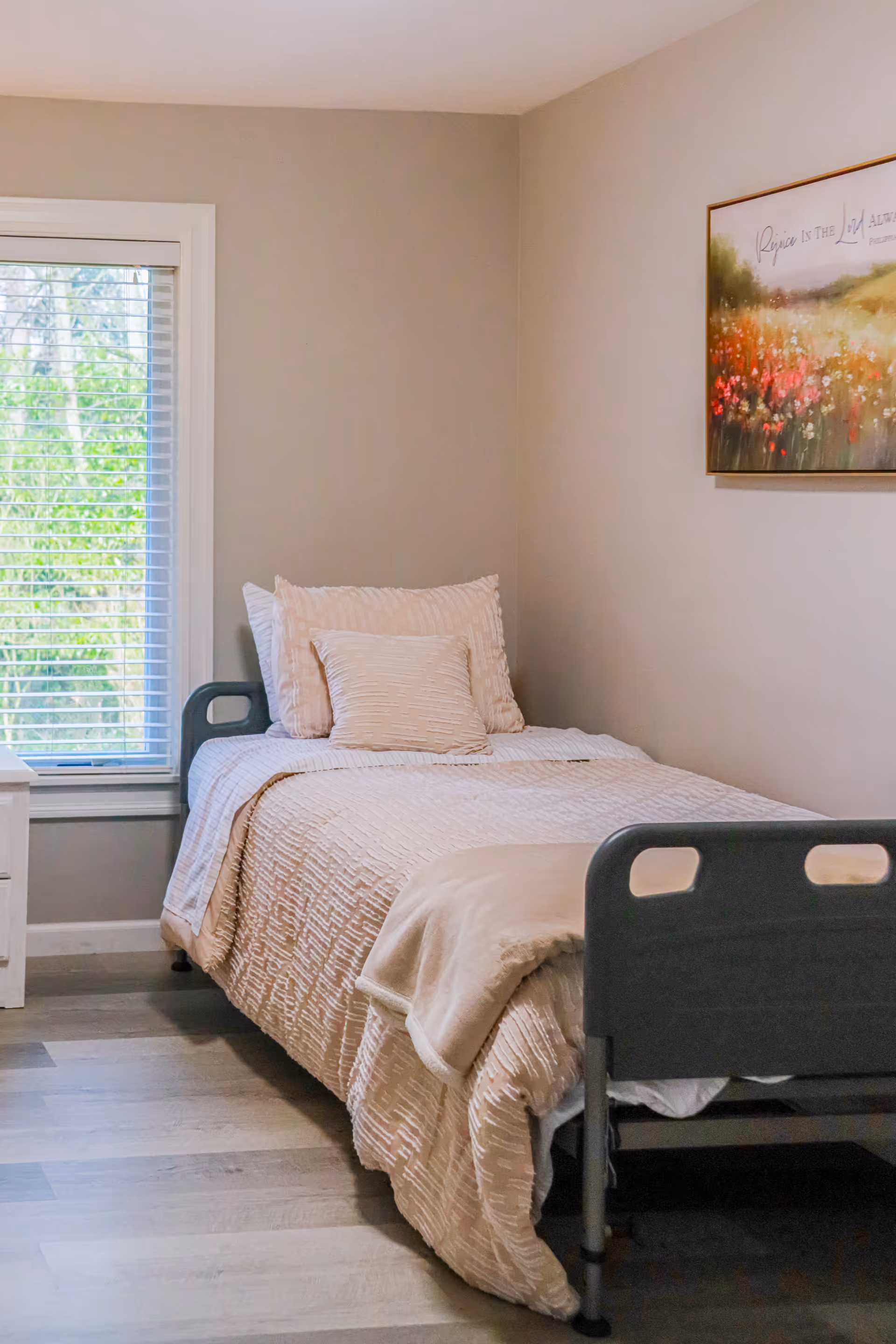 A neatly made bedroom with a single bed, window, and wall art.