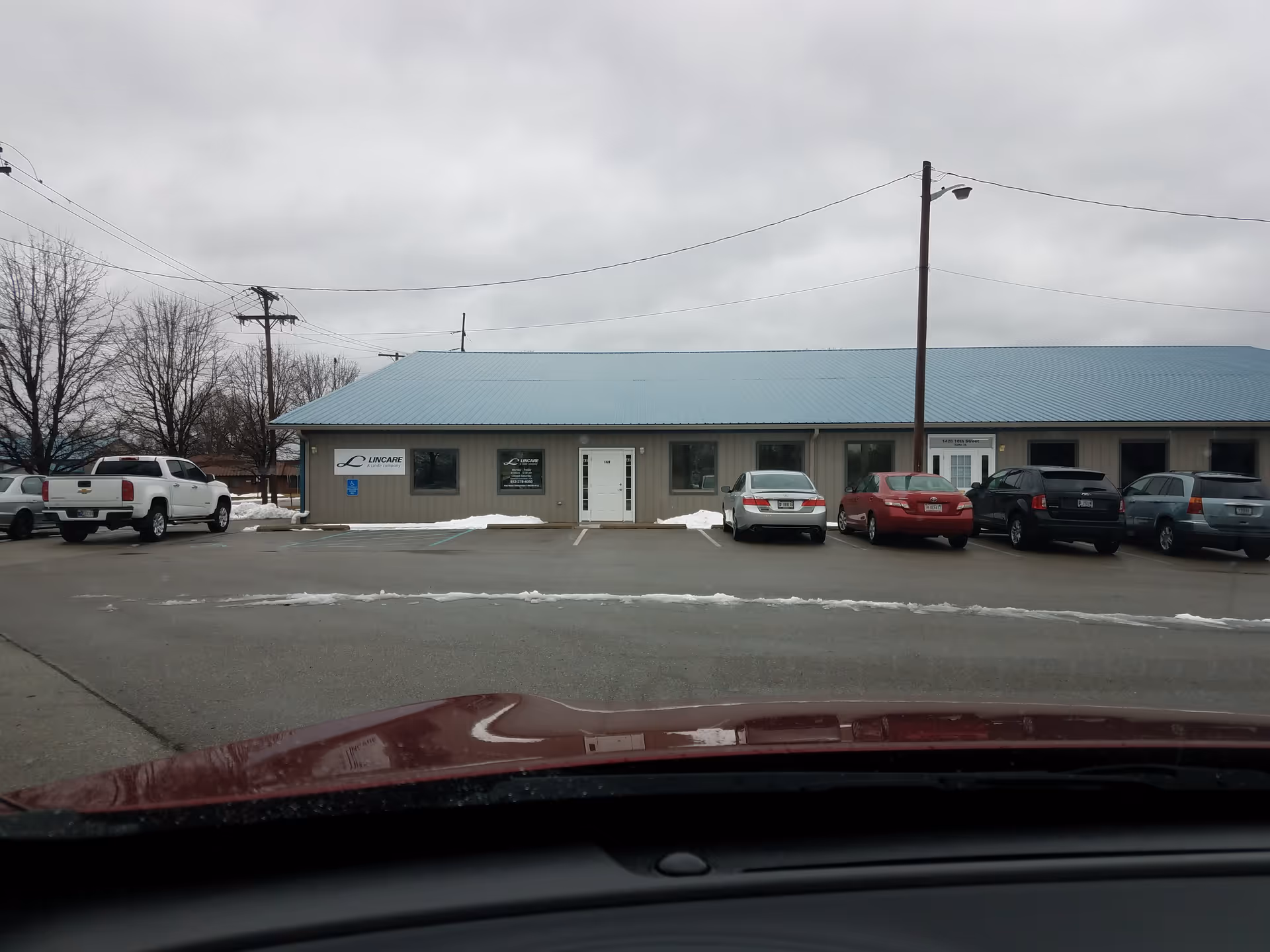 Exterior view of a single-story LINCARE facility with a blue roof and parking.