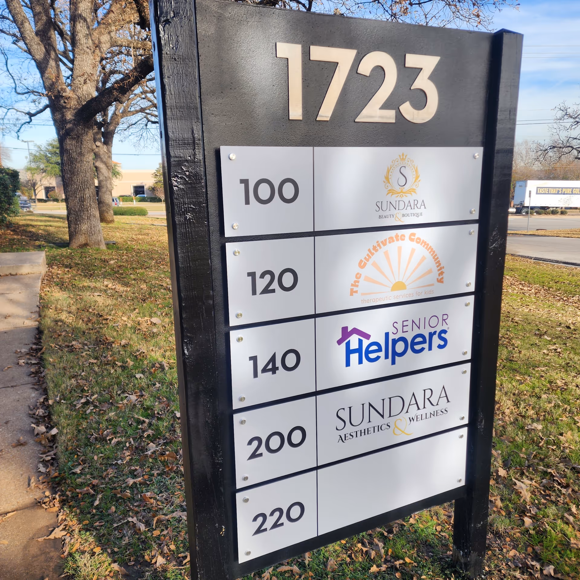 Outdoor signpost with multiple business plaques including Senior Helpers and Sundara.