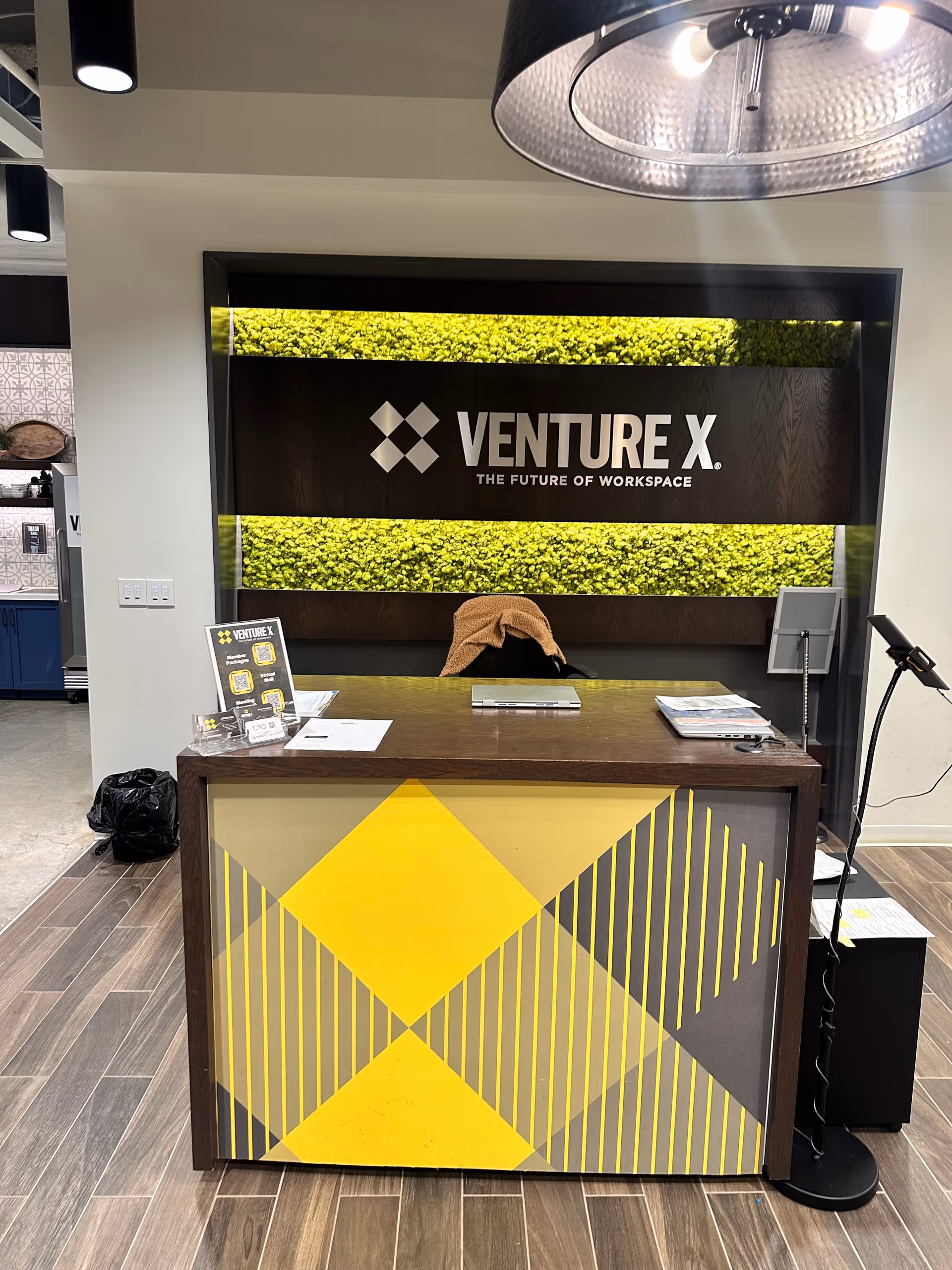 Reception desk in a modern interior with Venture X sign and yellow geometric panel.