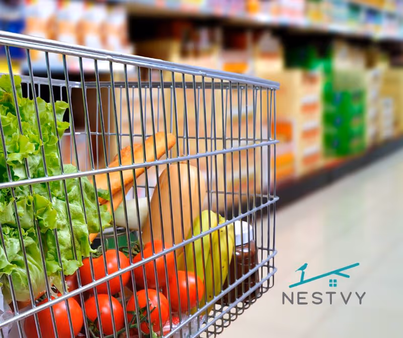 Shopping cart filled with fresh vegetables and fruits in a grocery store.