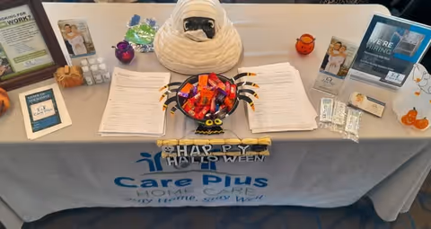 Promotional table for Care Plus Home Care with Halloween decorations and candy.