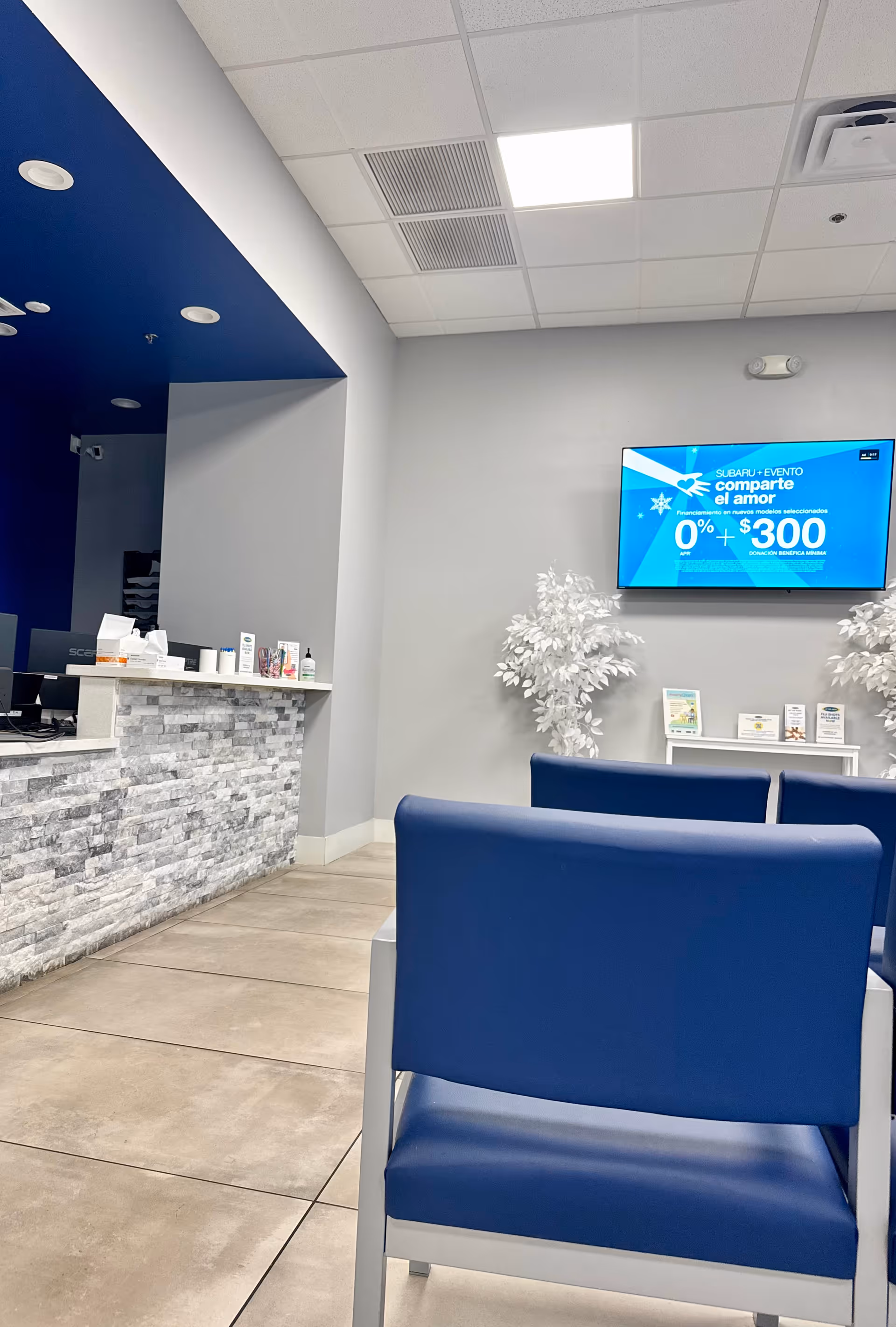 Lobby area with blue seating, a stone reception desk, and a wall-mounted TV.