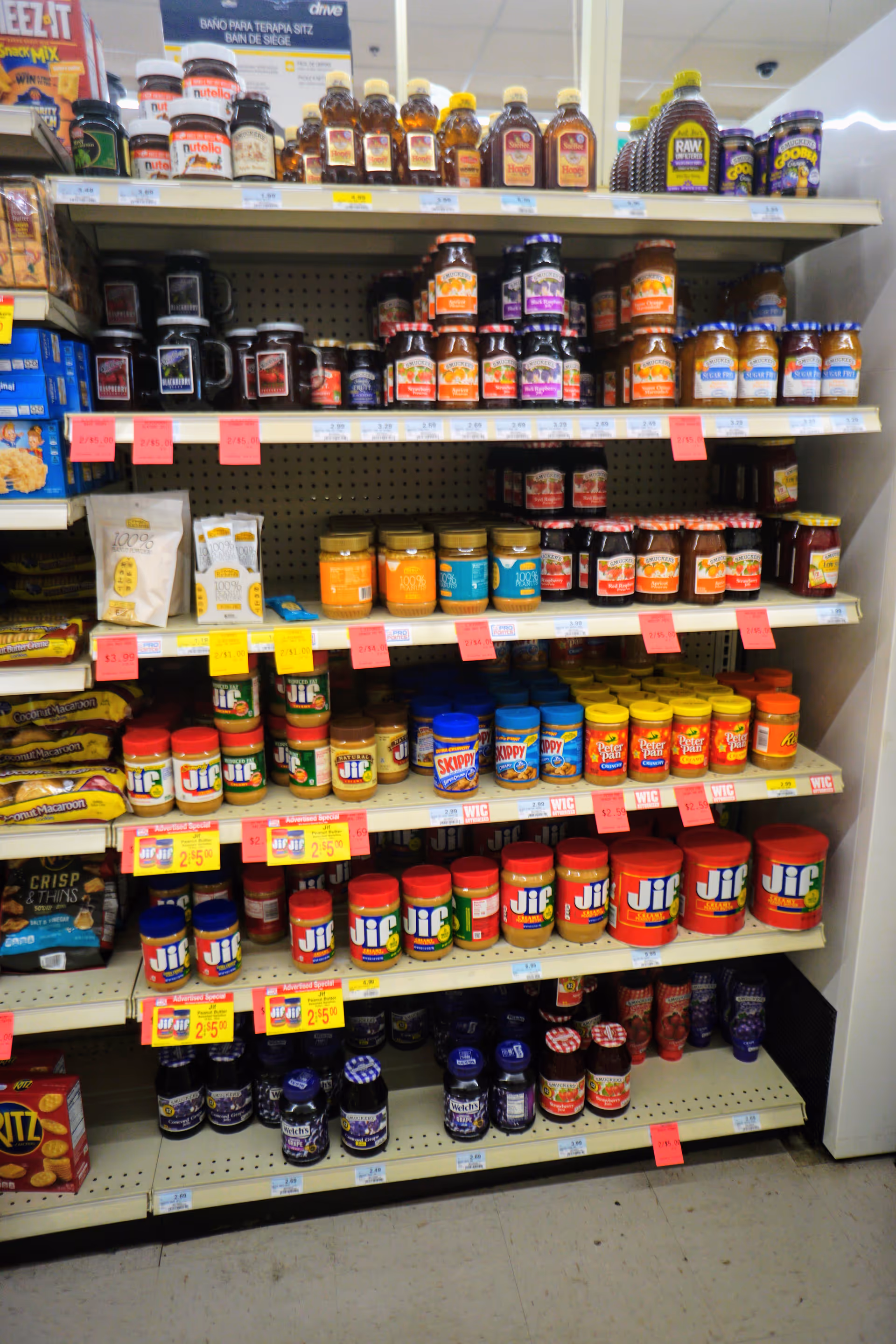 Grocery store aisle filled with shelves of peanut butter jars and spreads.
