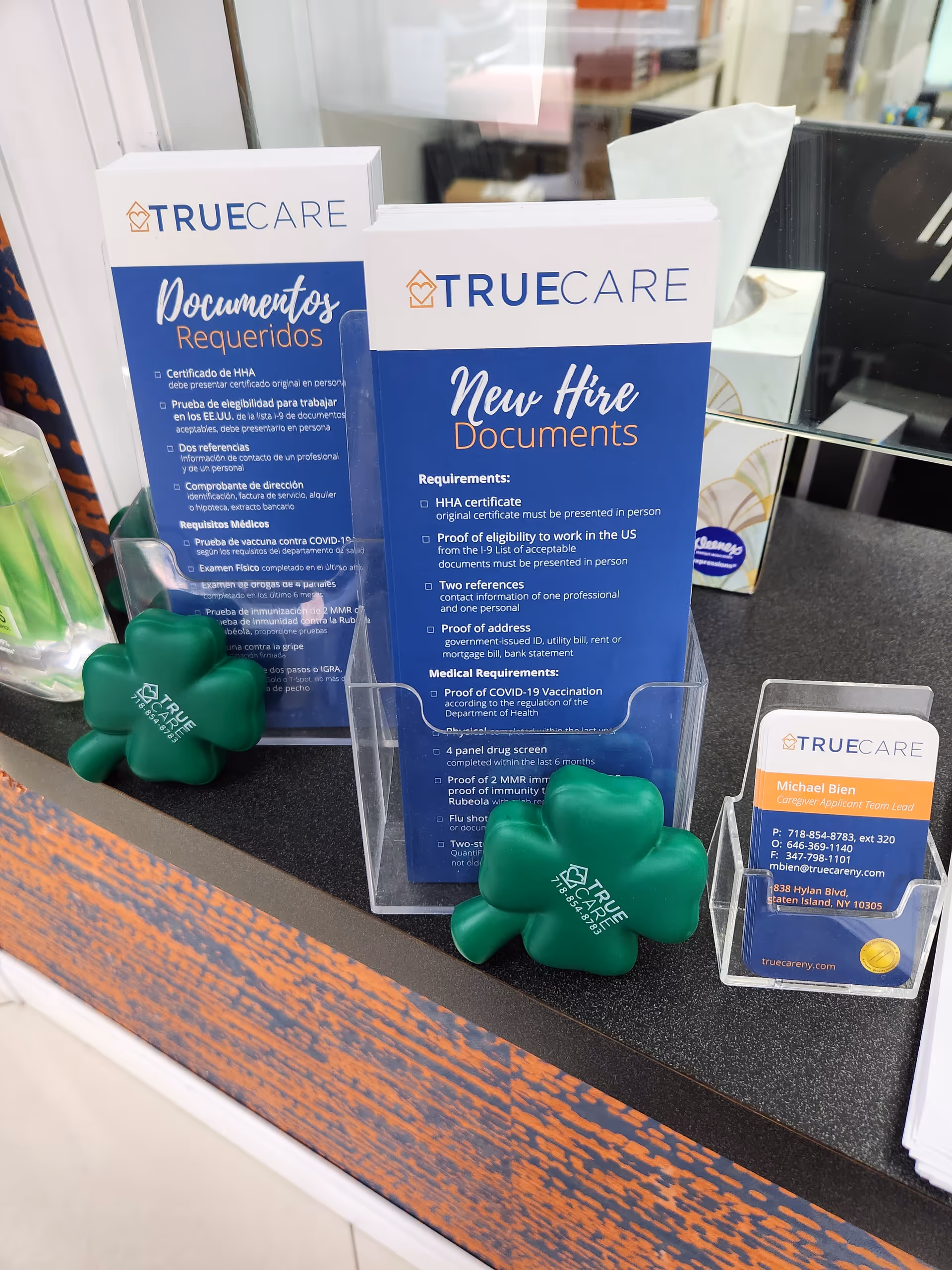 Reception counter with True Care documents, business cards, and green clover stress toys.