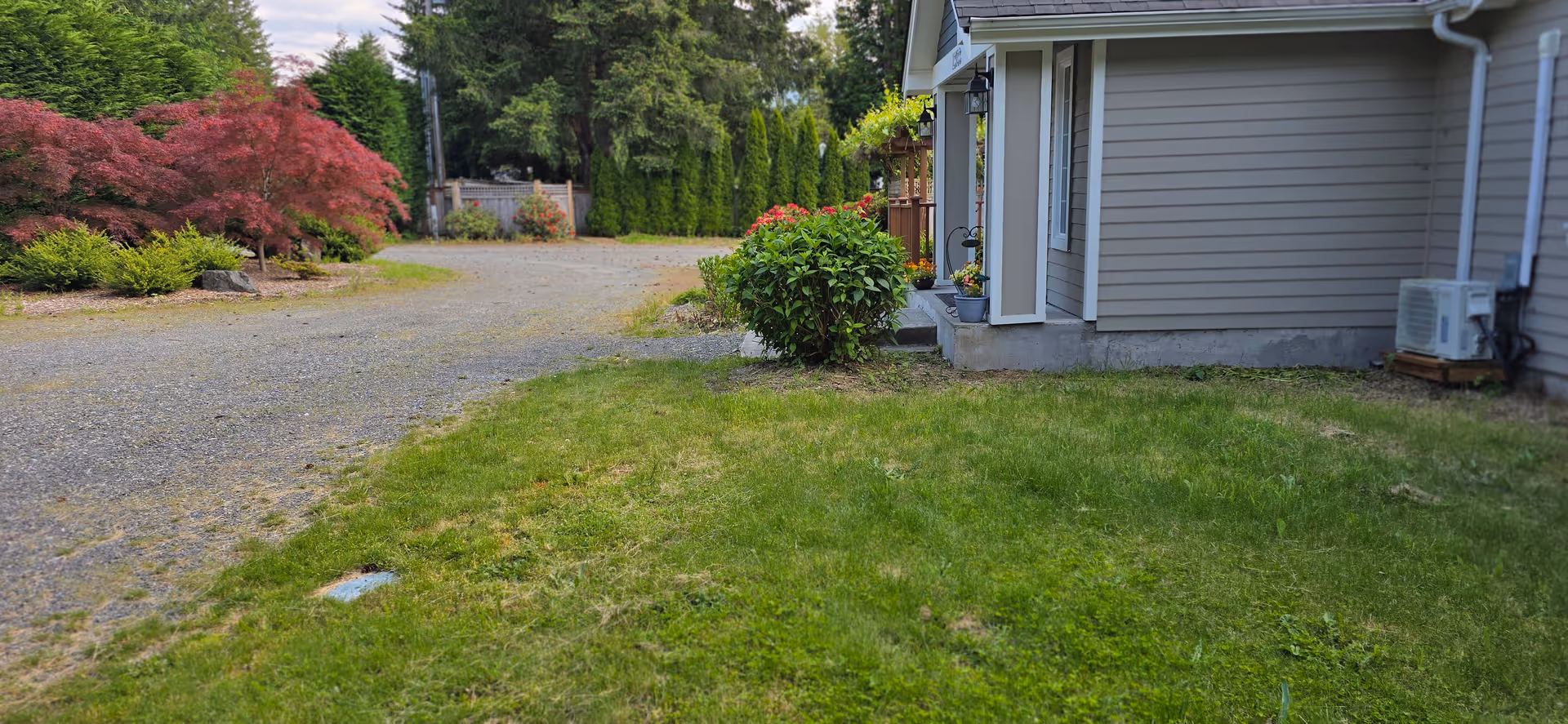 Exterior view of Snoqualmie Valley Senior Care building with lawn, shrubs, and driveway.