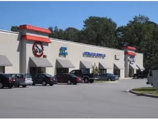 Exterior view of a LINCARE facility with storefronts and several parked cars.