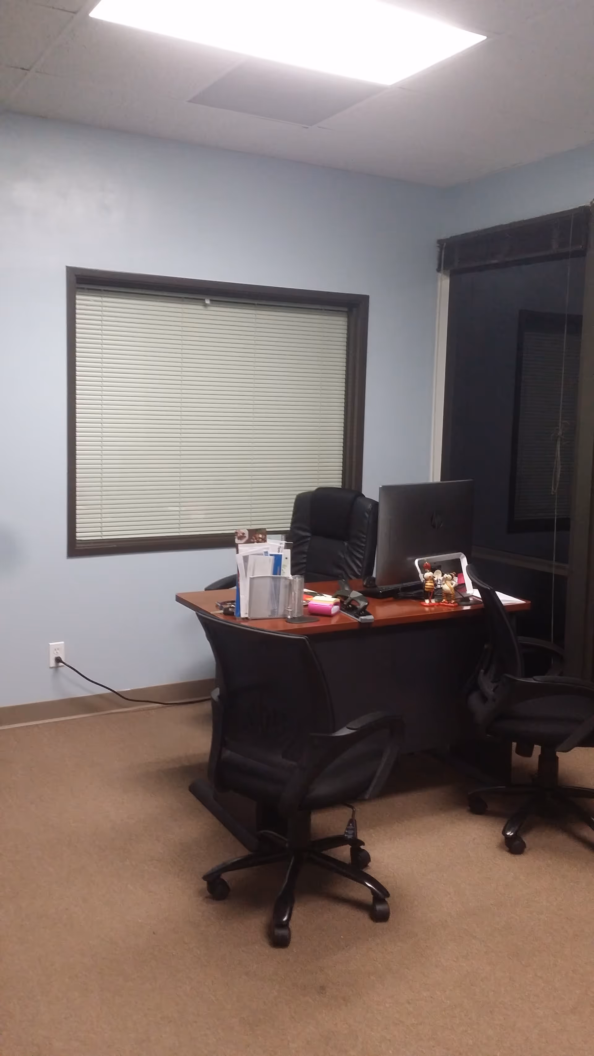 Office desk with computer and chairs in a blue-walled, well-lit room.