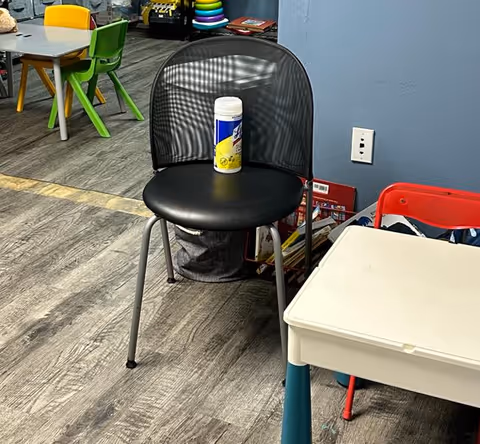 A black chair with a bottle resting on it in a colorful playroom.