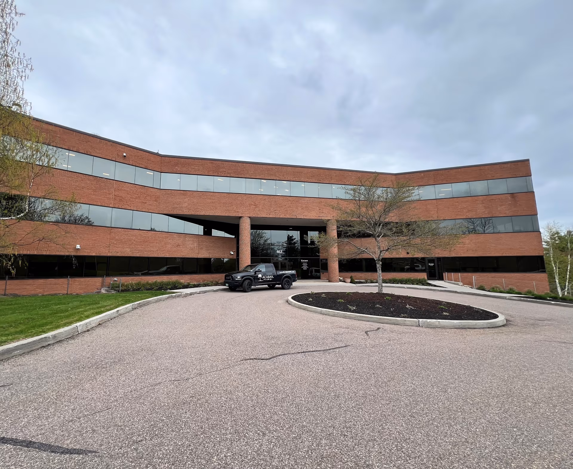 Curved brick facility with large glass windows and a front driveway.