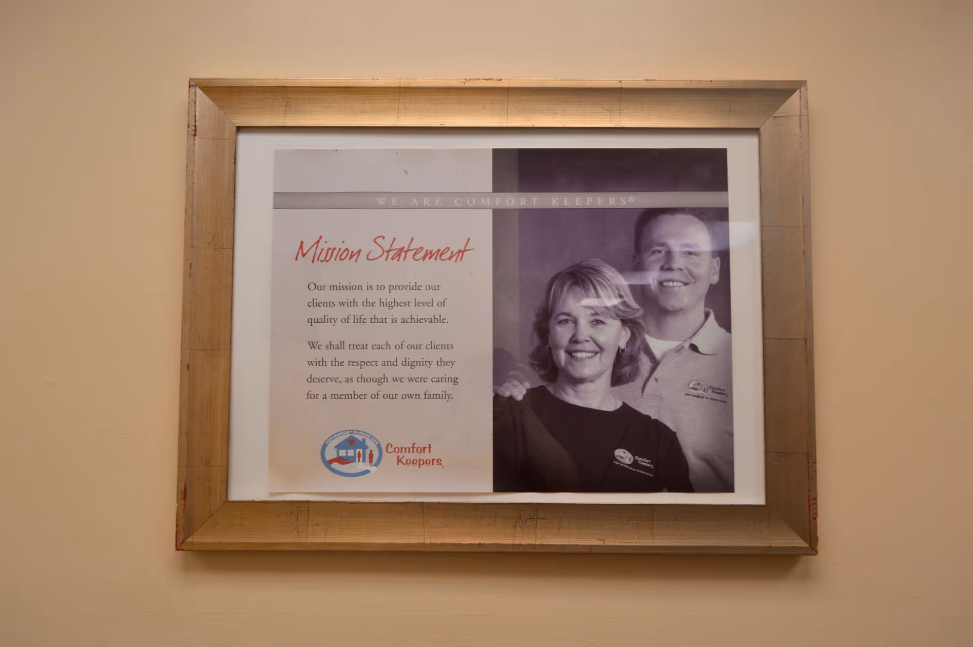 Framed poster on a wall showing the mission statement and two people.