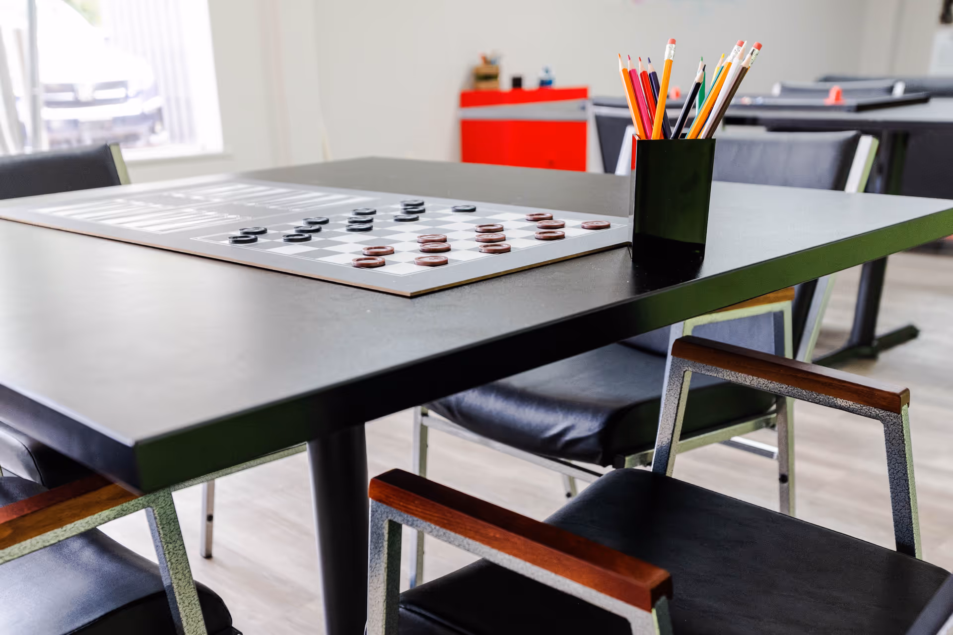 Indoor activity room with a checkers board and pencil cup on a table.