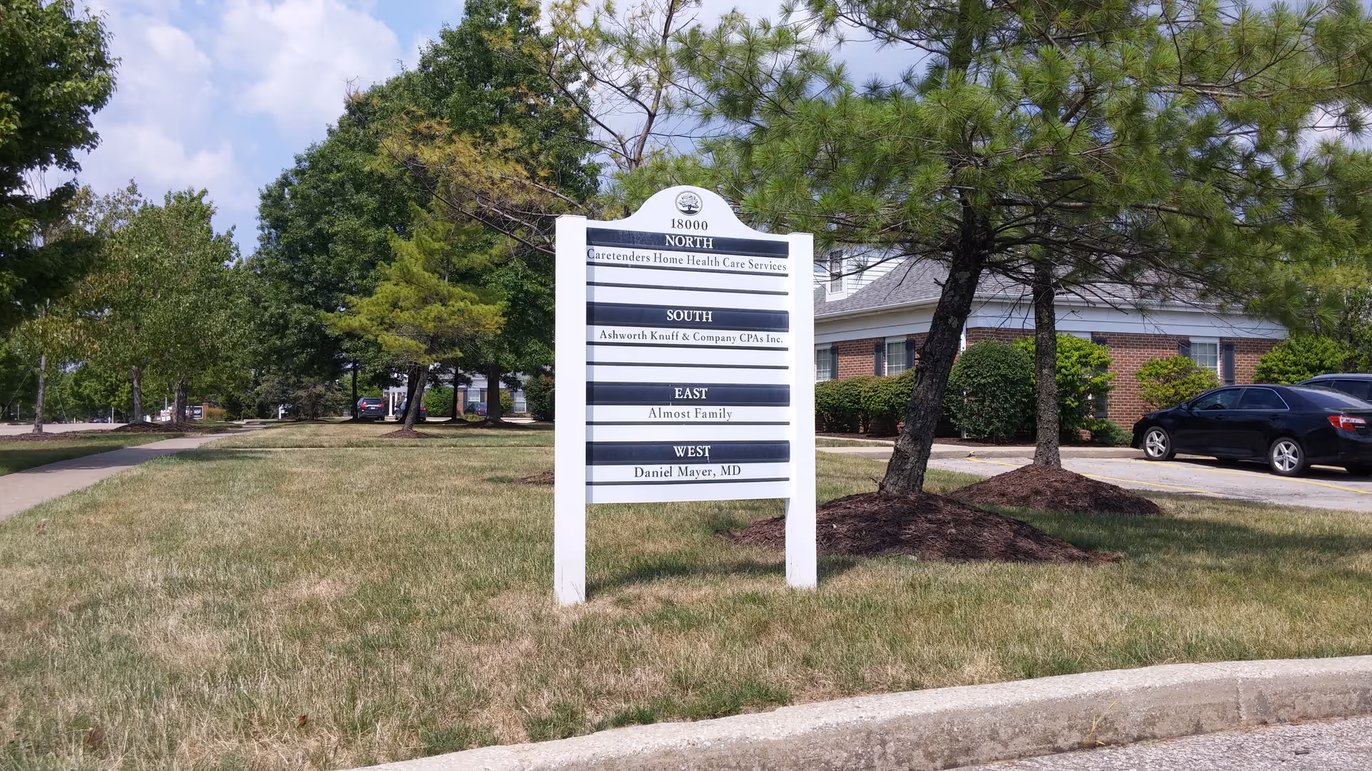 Exterior view of Caretenders facility with a white sign and trees.