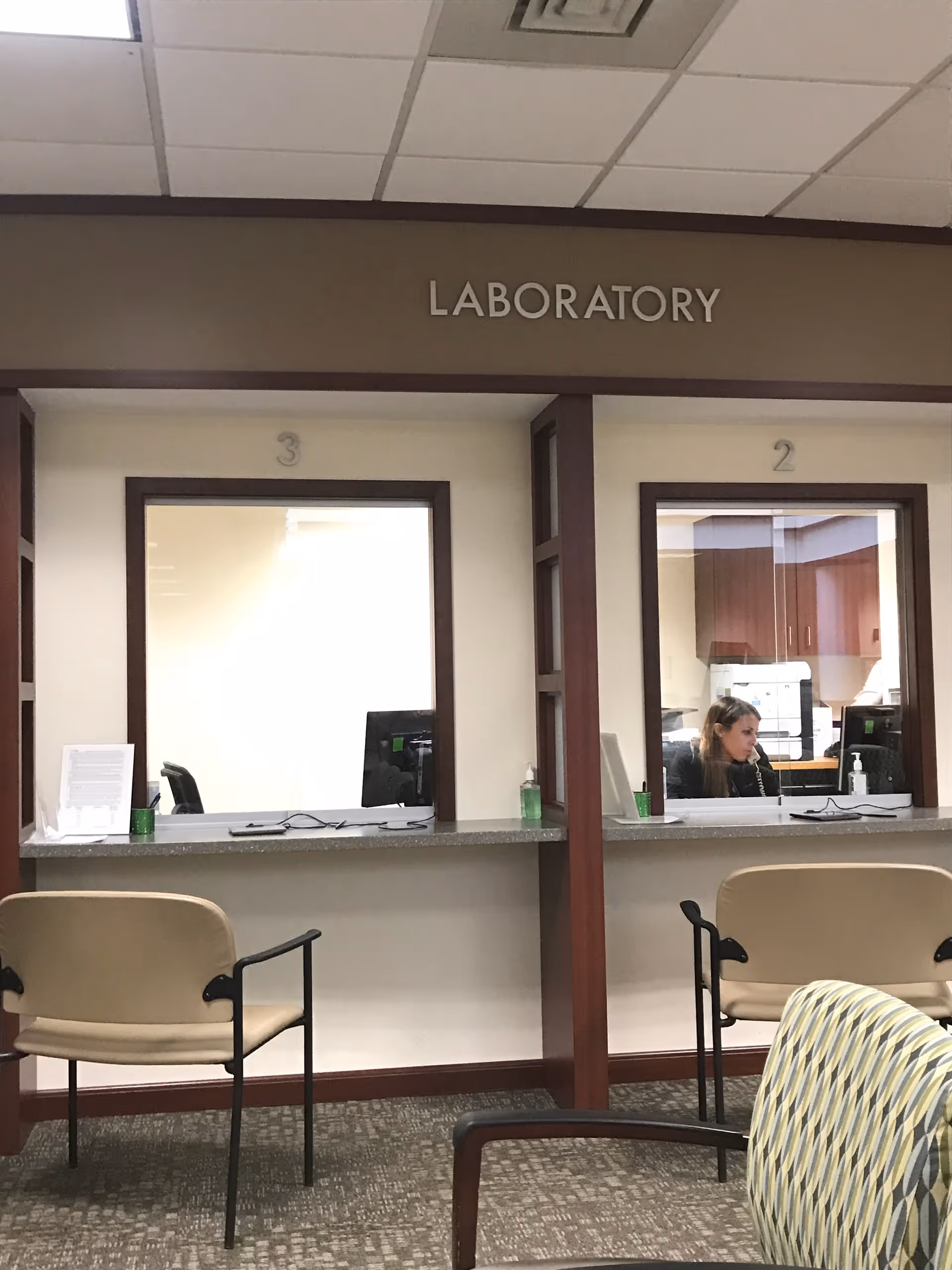 Interior of a clinical reception area labeled Laboratory, showing two service windows and chairs.