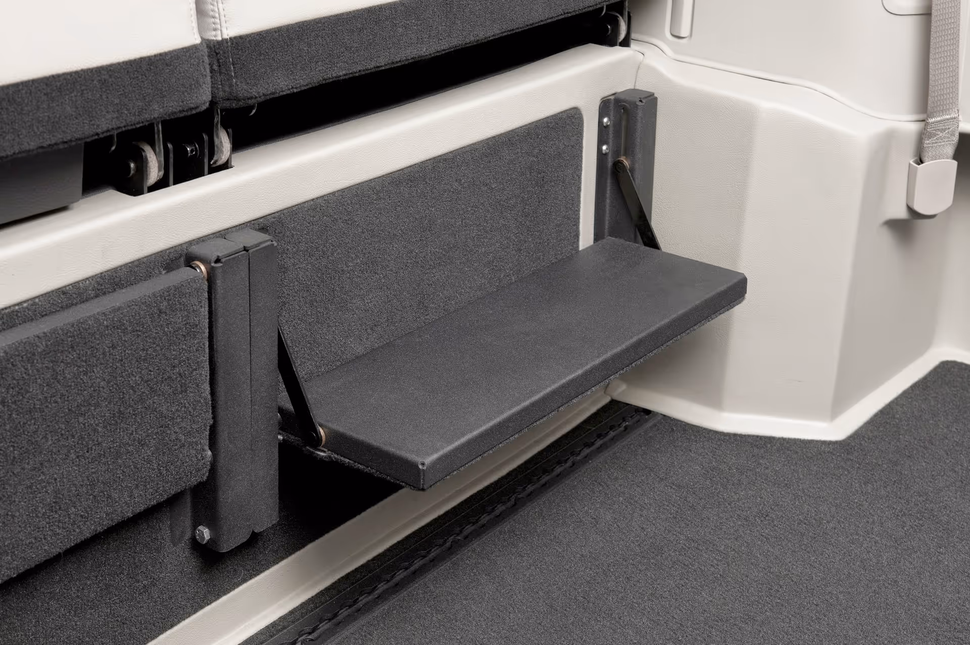 Close-up of a fold-out black wheelchair step inside a vehicle with a carpeted floor.