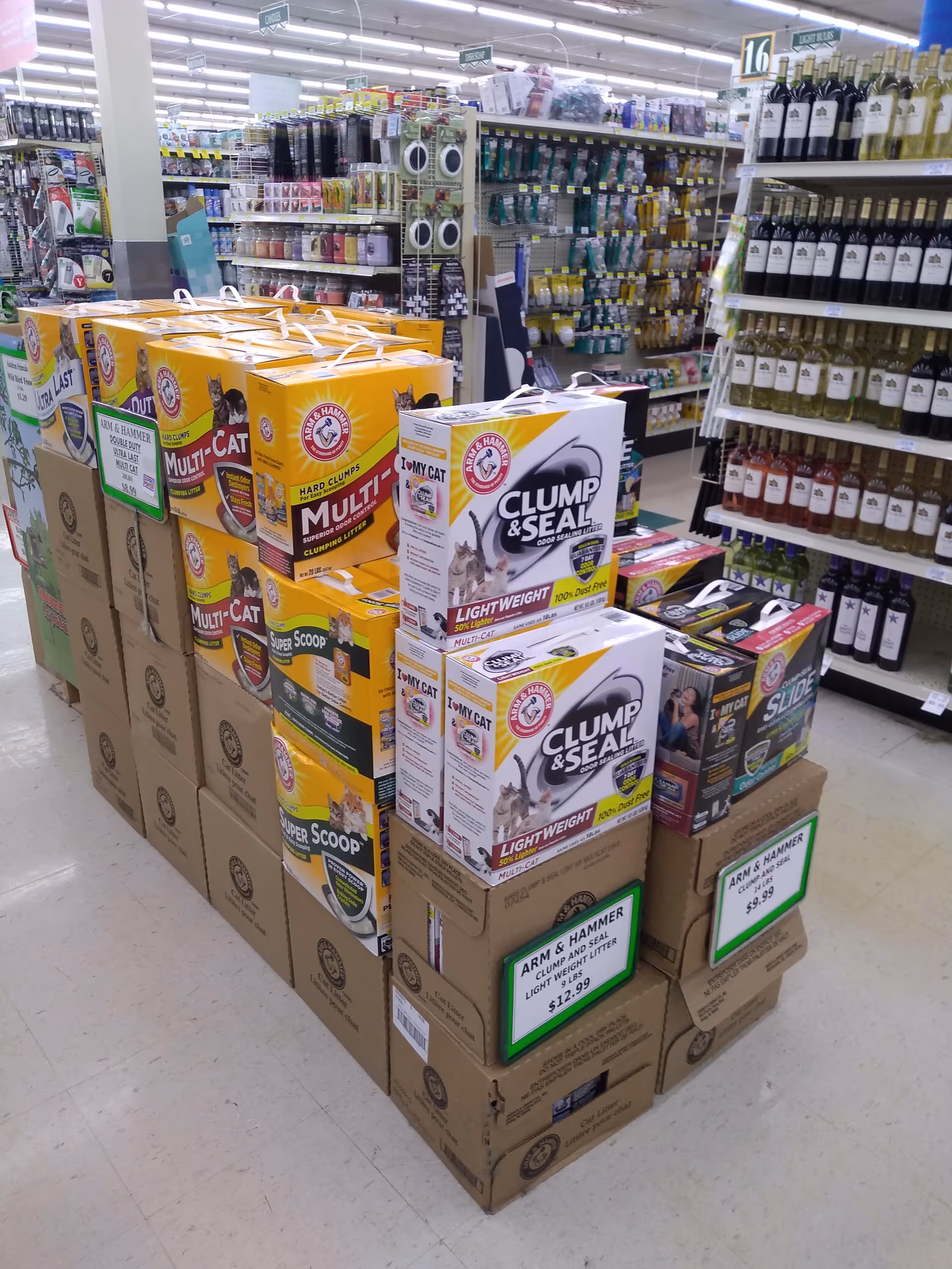 Stacked boxes of cat litter and store shelves fill a bright aisle.