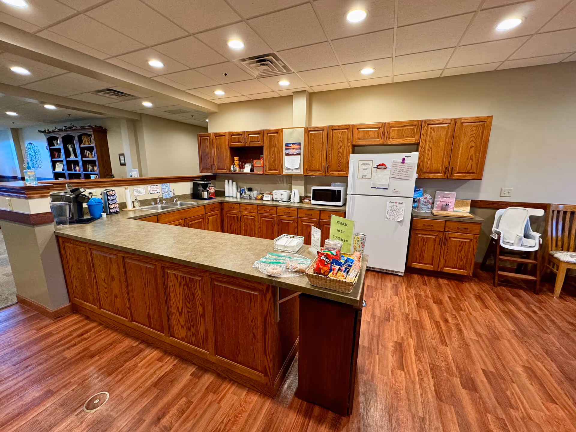 A spacious facility kitchen with wooden cabinets, a long island, and assorted appliances.