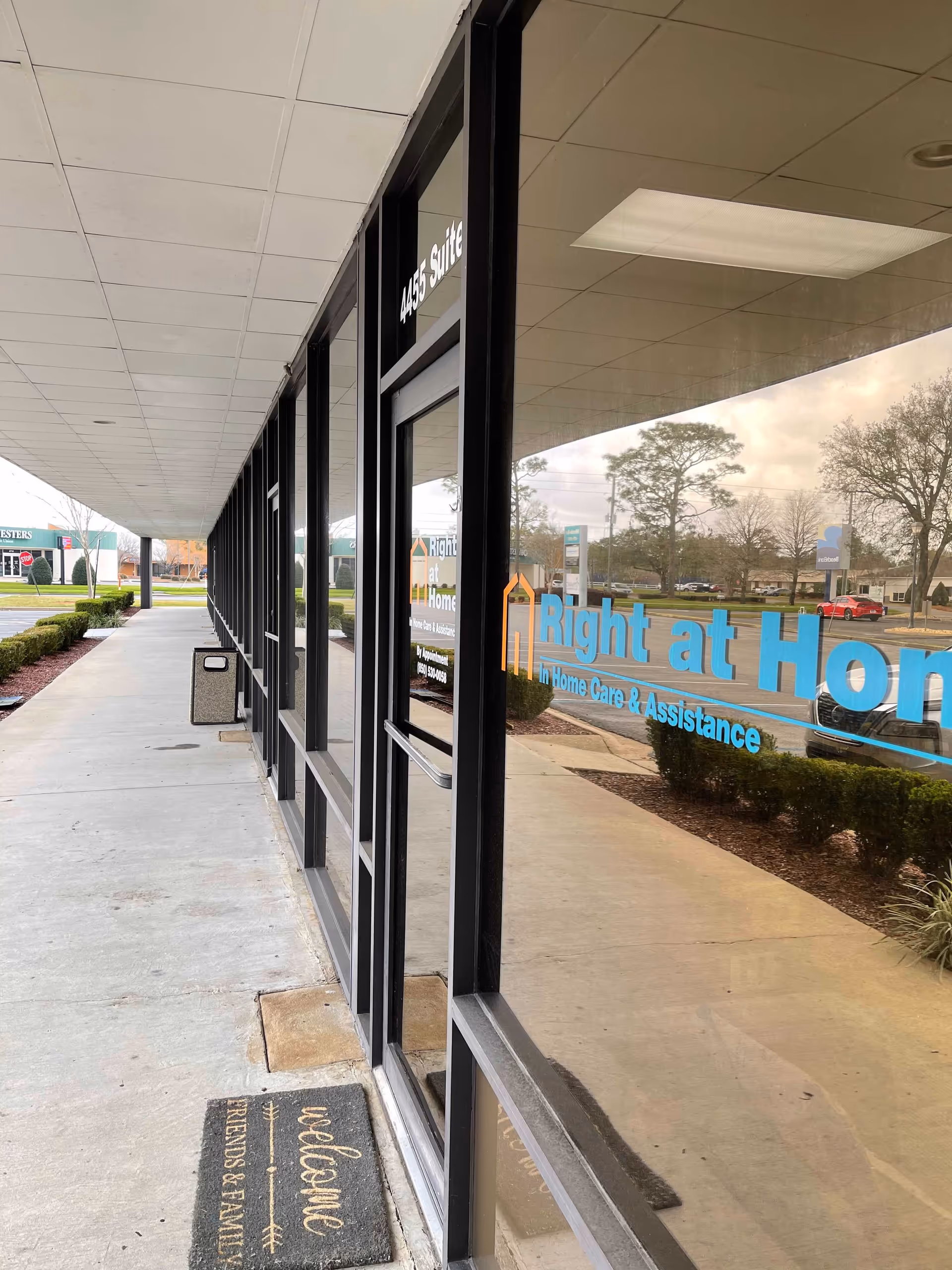 Exterior view of Right at Home entrance with glass doors and a sidewalk along the storefront.