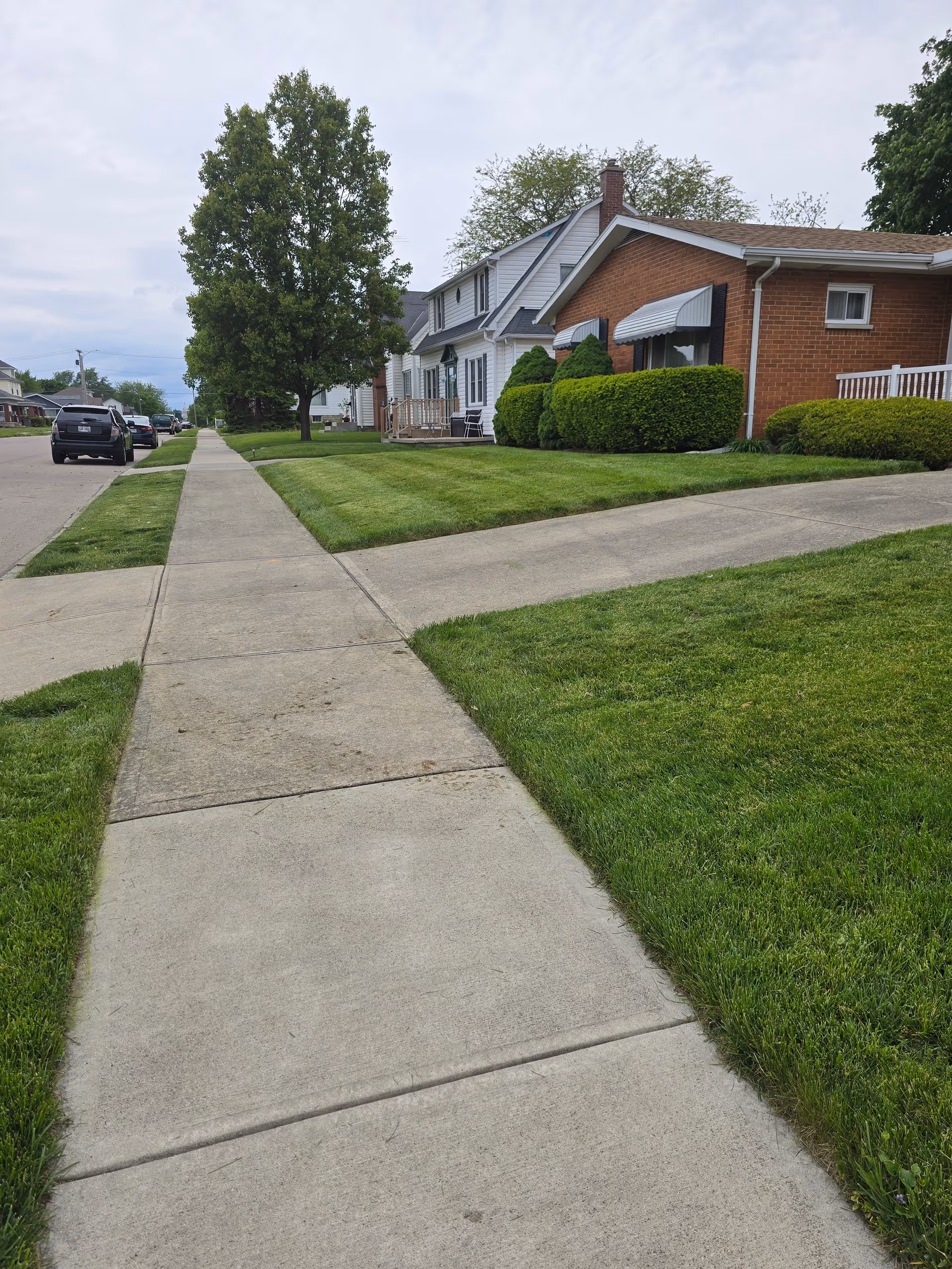 Exterior view of a senior living facility with brick front, green lawns, and sidewalk