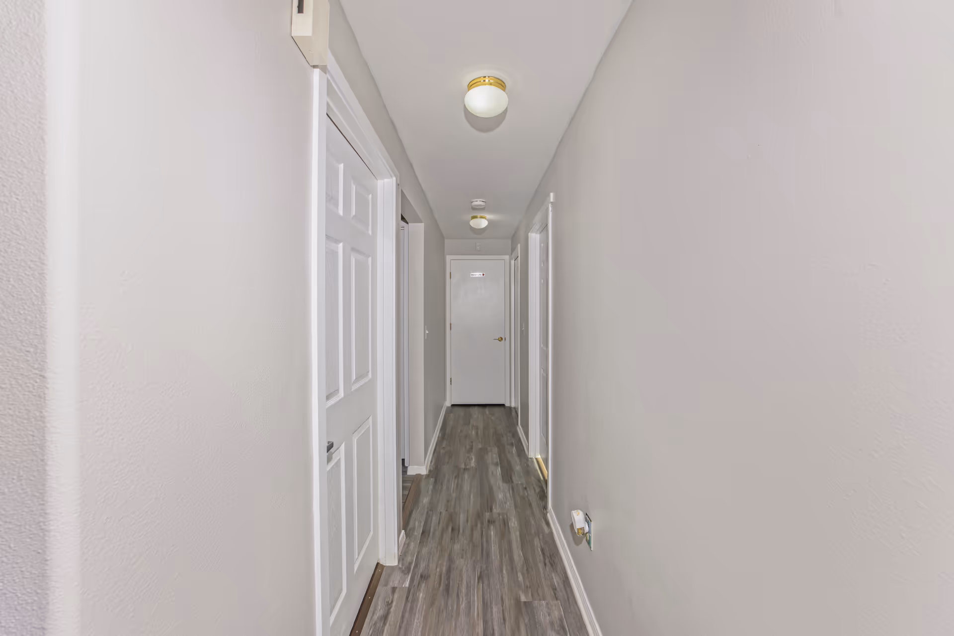 Long, narrow hallway at Clover Care Adult Family Home with closed doors along both sides.