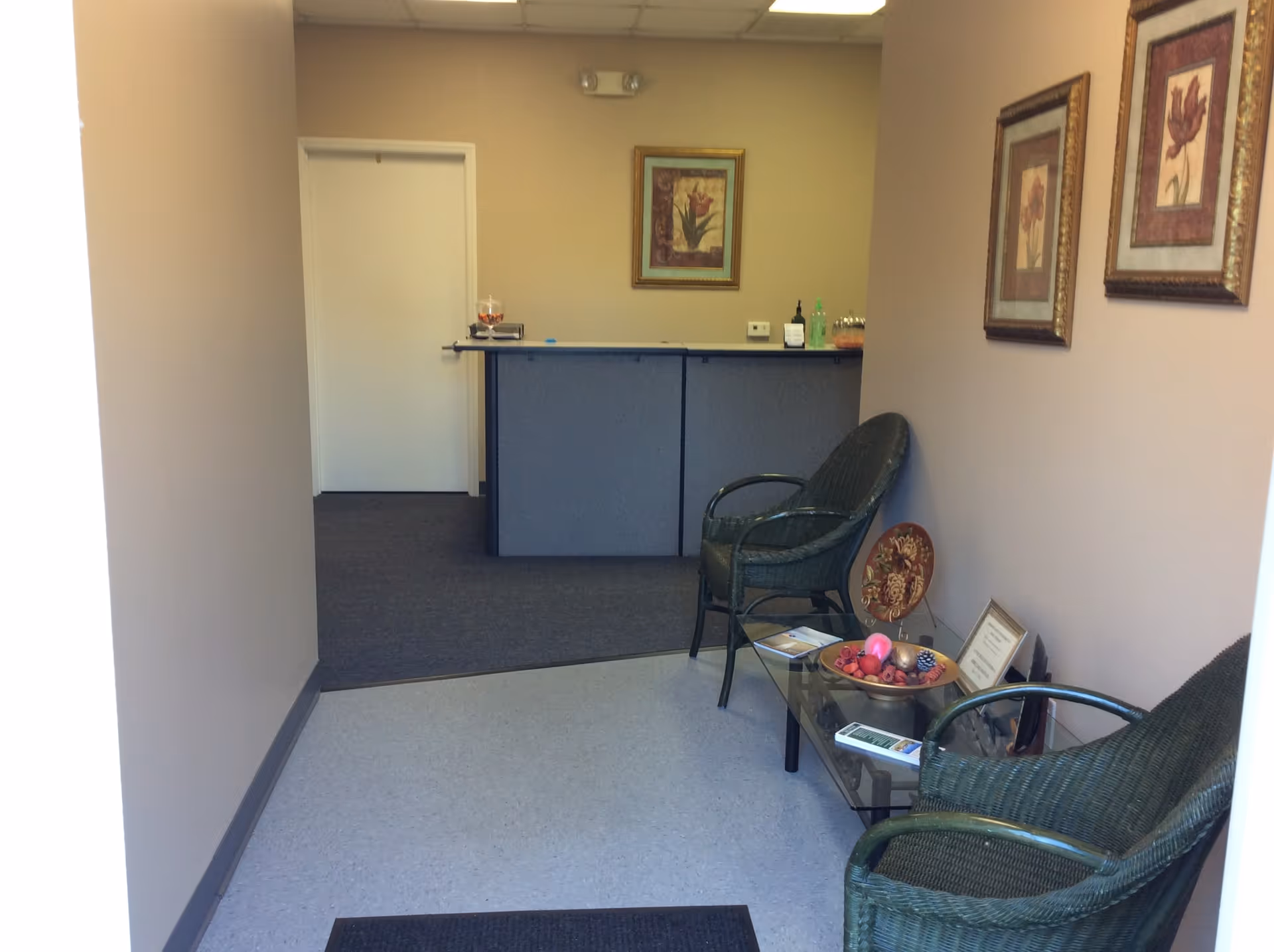A quiet facility lobby with chairs, a glass coffee table, and framed artwork.