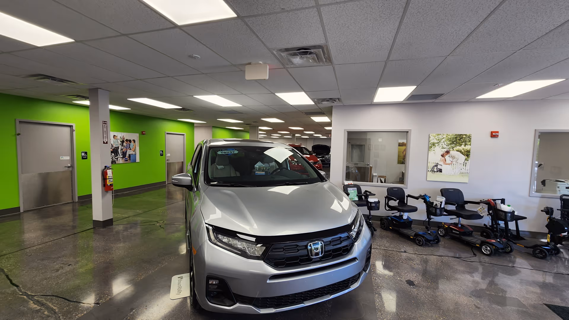 Silver Honda SUV inside a mobility showroom with scooters and seating along the wall