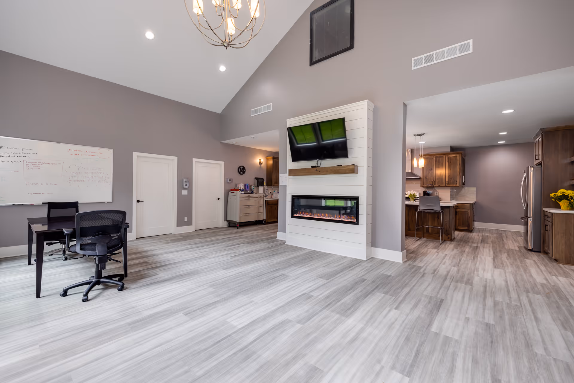 Open, modern interior with a wall-mounted TV above a fireplace and adjacent kitchen.