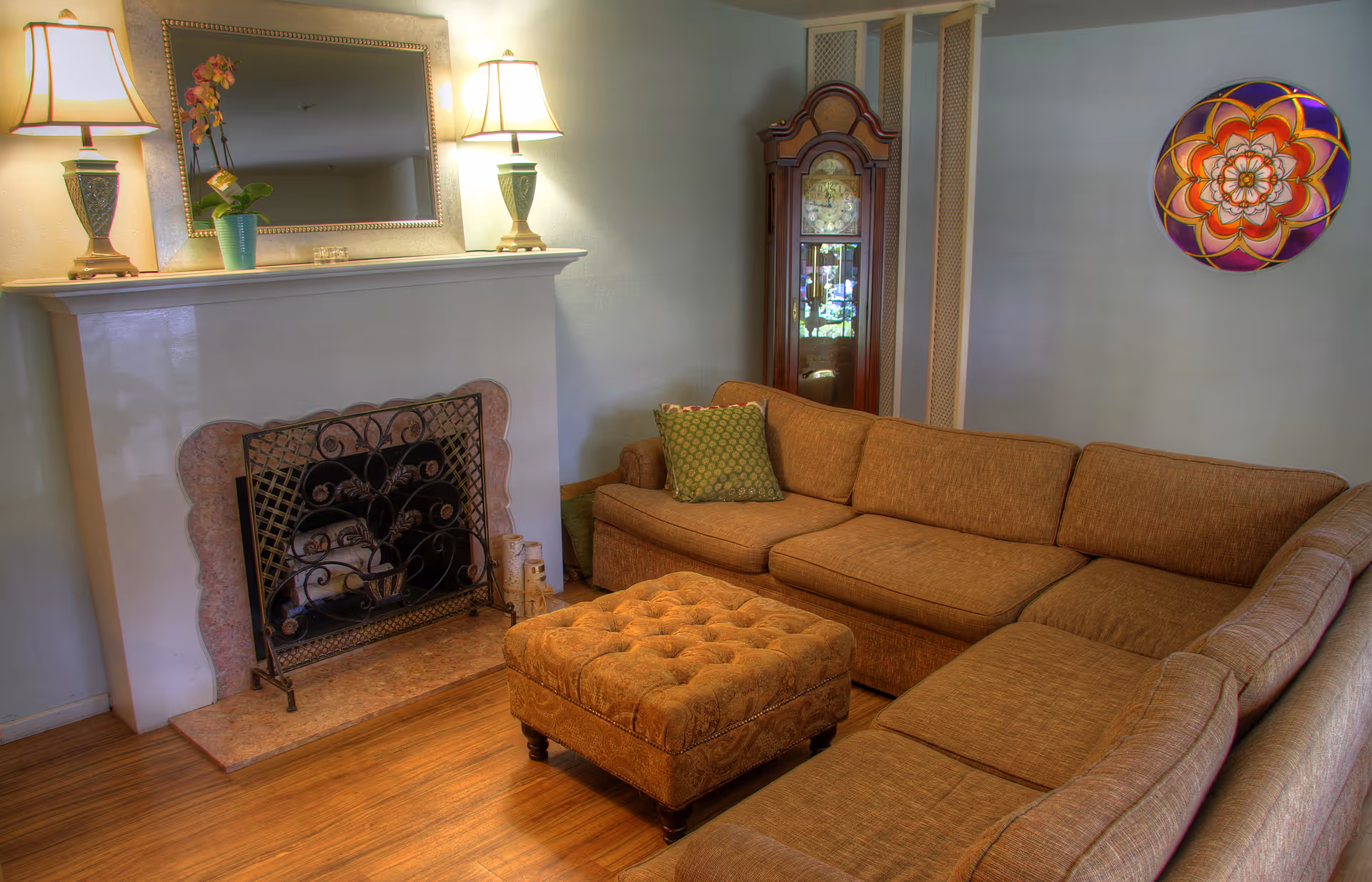 Cozy living room with L-shaped sofa, ottoman, fireplace, and decorative wall plate.