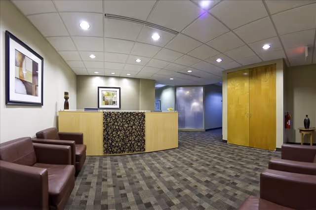 A senior living facility reception area with a curved wooden desk, seating, and framed art.