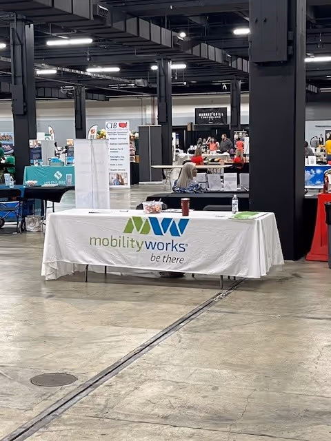 Indoor expo hall with a MobilityWorks table and vendor booths in the background.