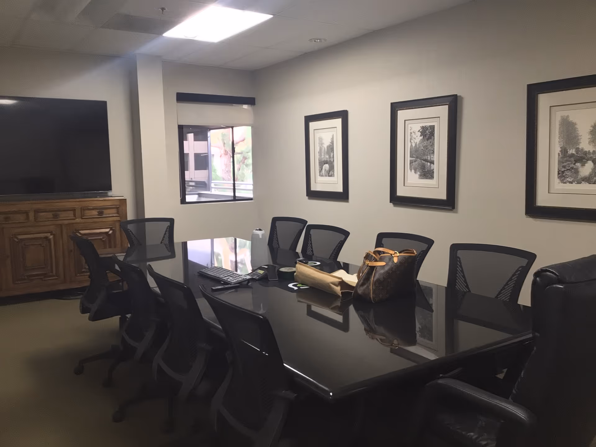 Interior conference room with glass table, black chairs, and framed wall art.