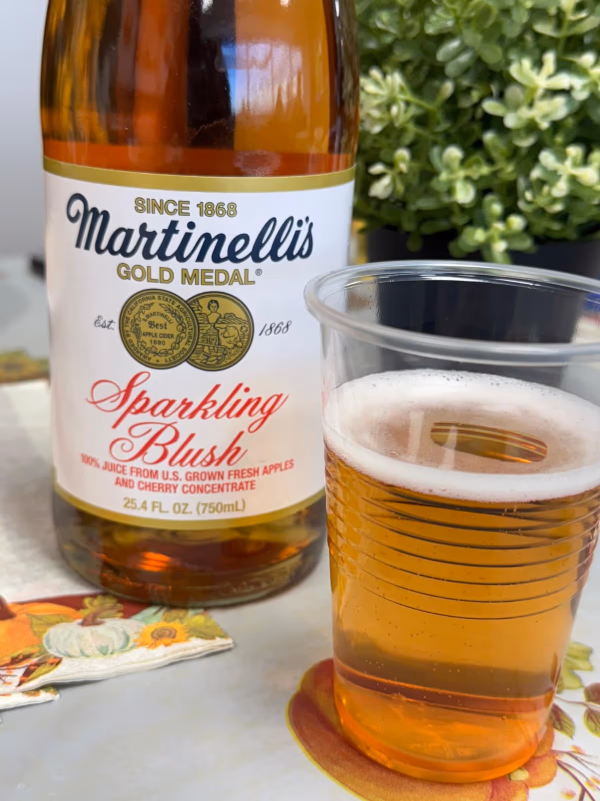 Close-up of Martinelli's Sparkling Blush bottle beside a glass on a table.
