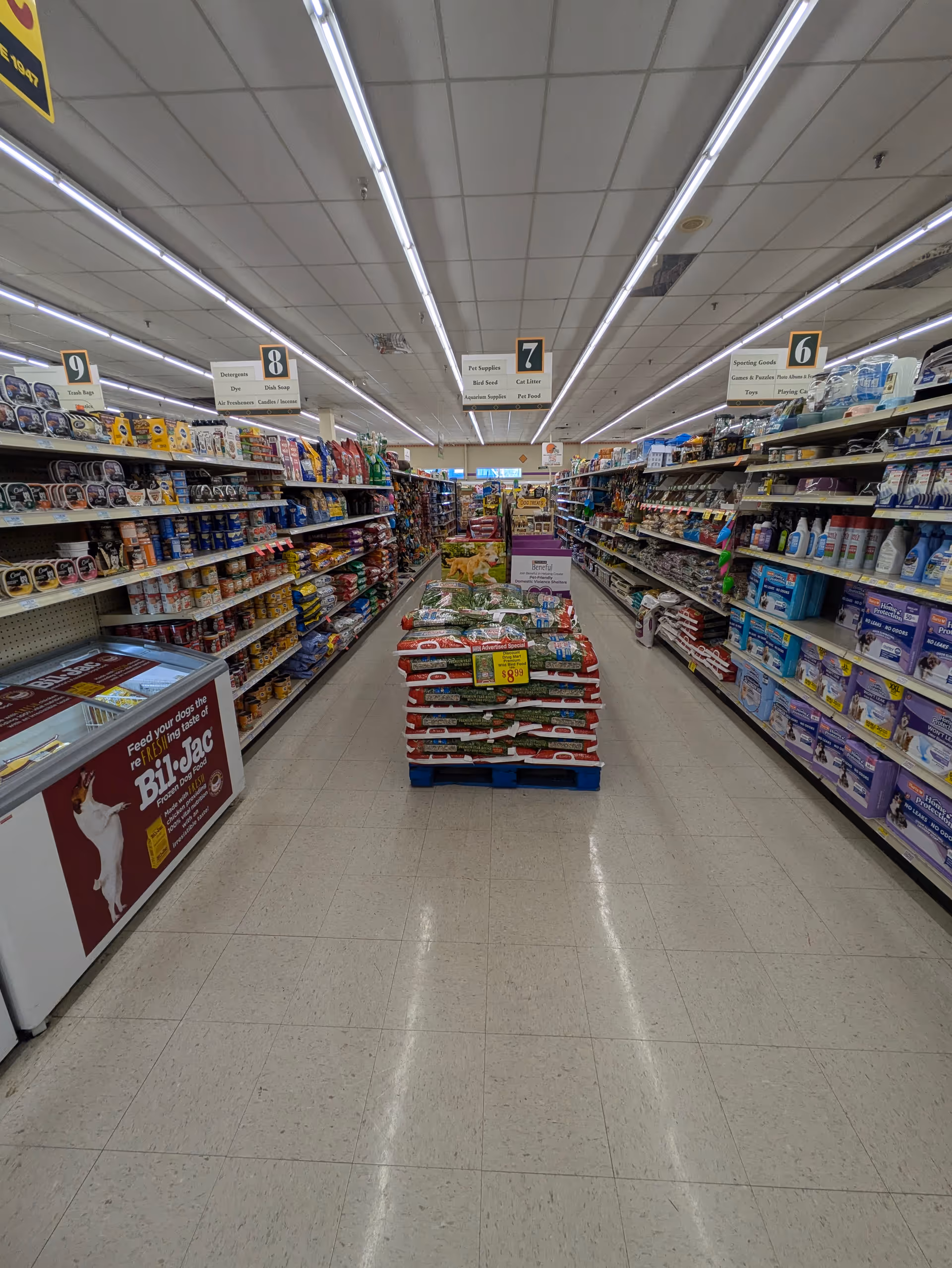 A wide grocery store aisle with shelves filled with products on both sides.