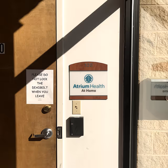 Entrance to Atrium Health At Home with a warning sign on a wooden door.