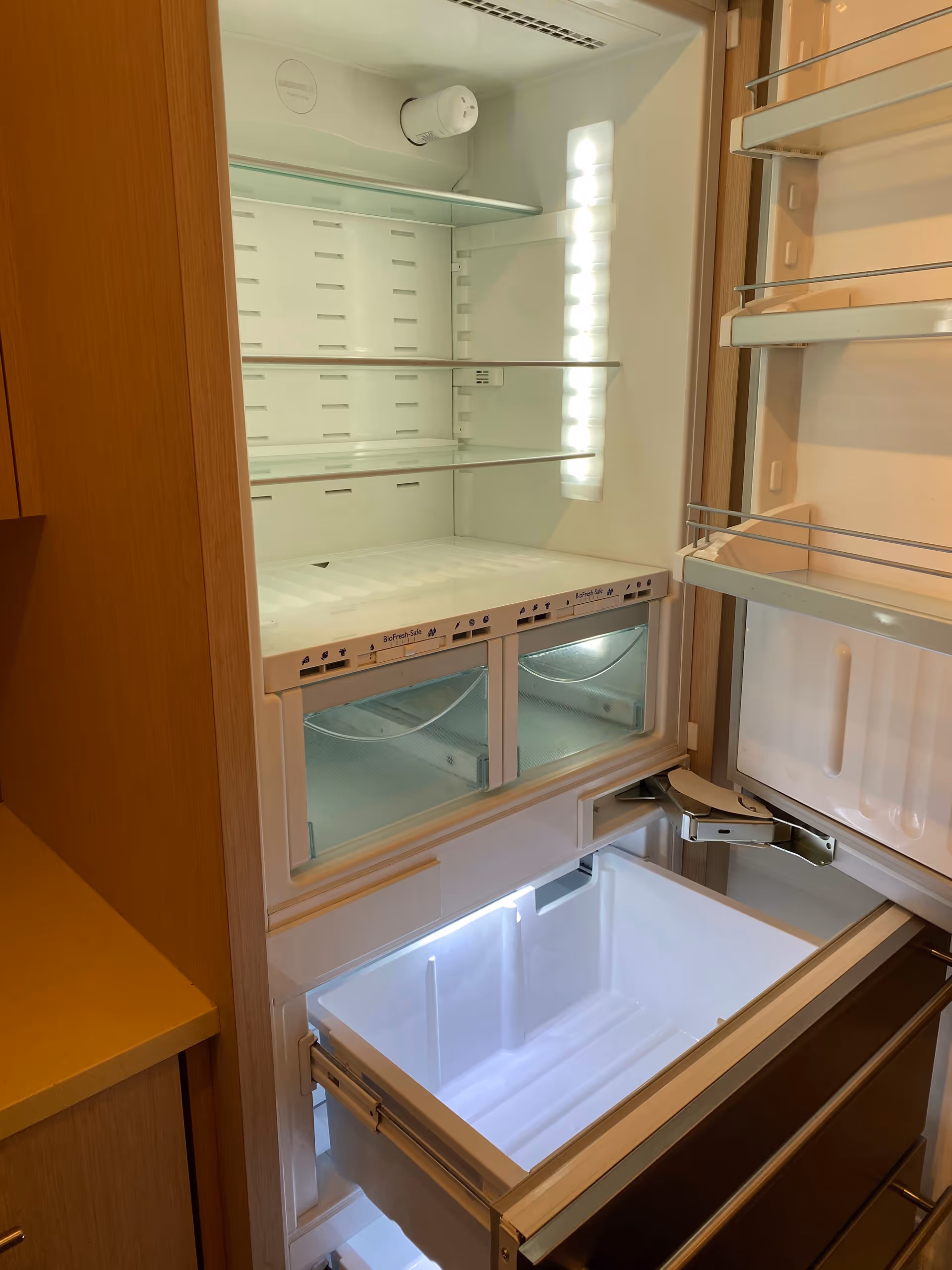 Open refrigerator with empty shelves and drawers in a modern kitchen.
