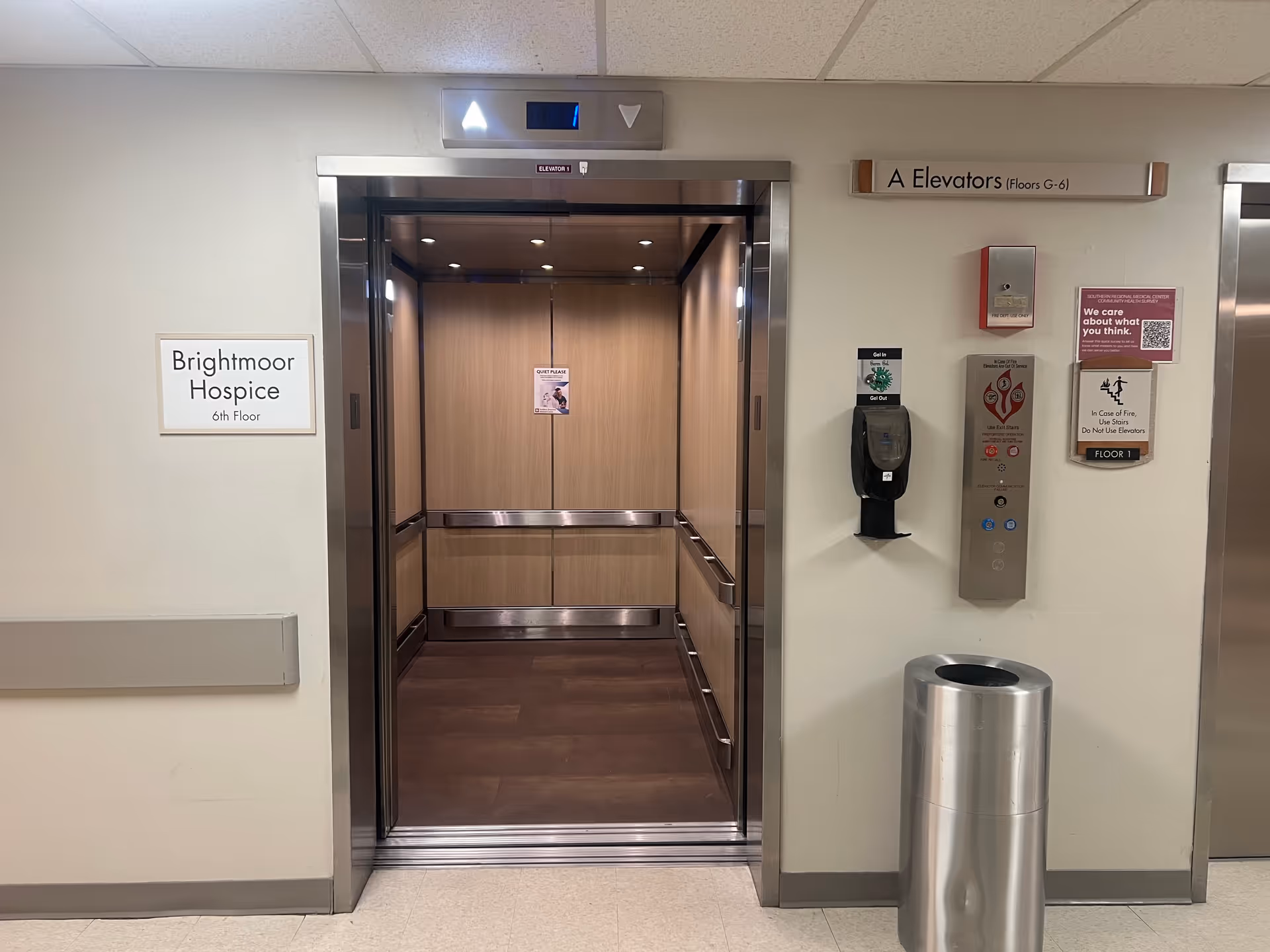 Elevator doors open in a hospital hallway with Brightmoor Hospice signage.