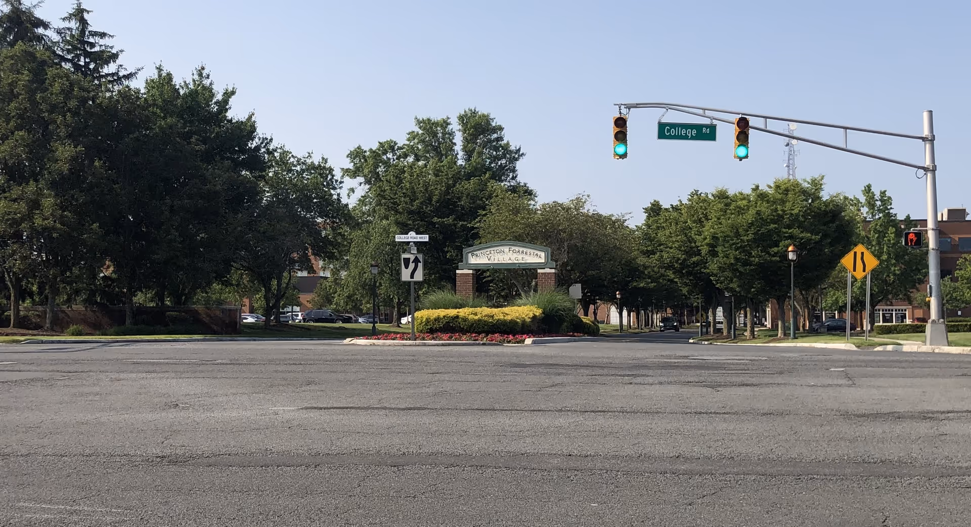 Intersection with traffic lights, trees lining the street, and a landscaped entrance sign.
