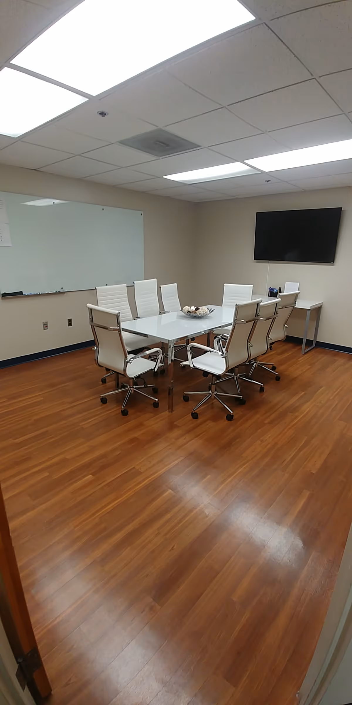 Modern conference room in a senior living facility with a glass table and white chairs.