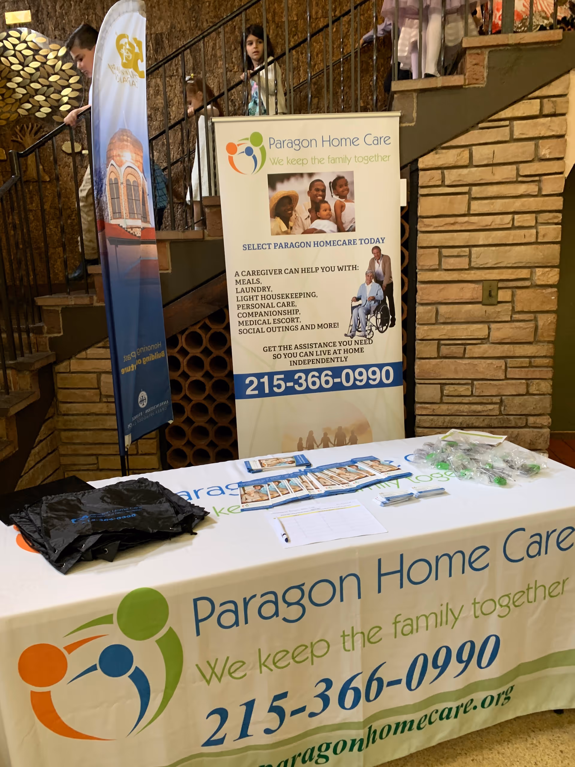 Indoor informational booth for Paragon Home Care with banner, table, and brochures.