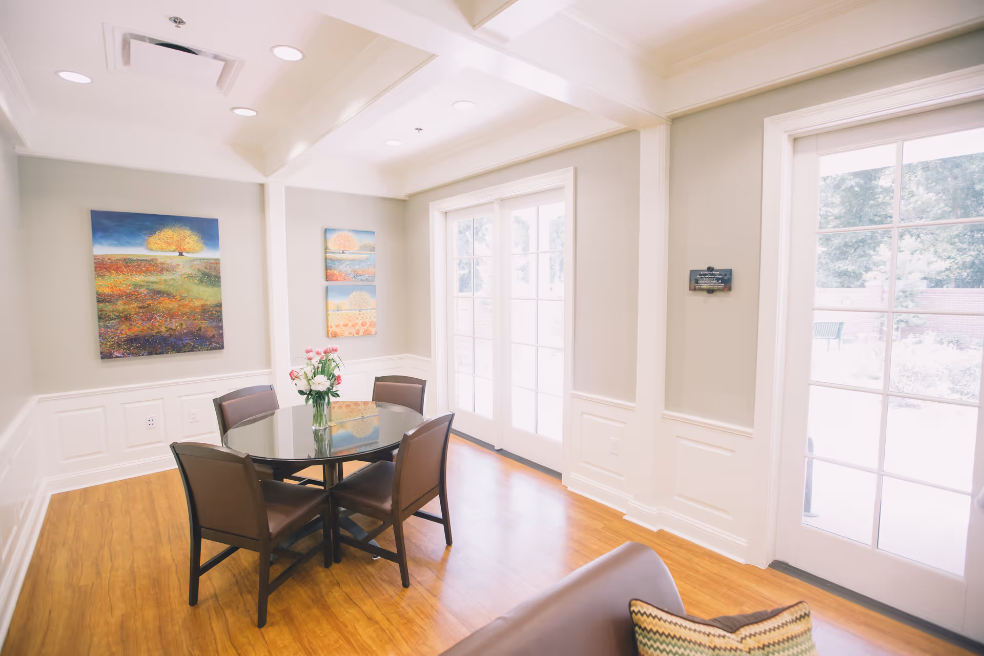 Bright, airy dining area with round glass table, four chairs, and French doors to outdoors.