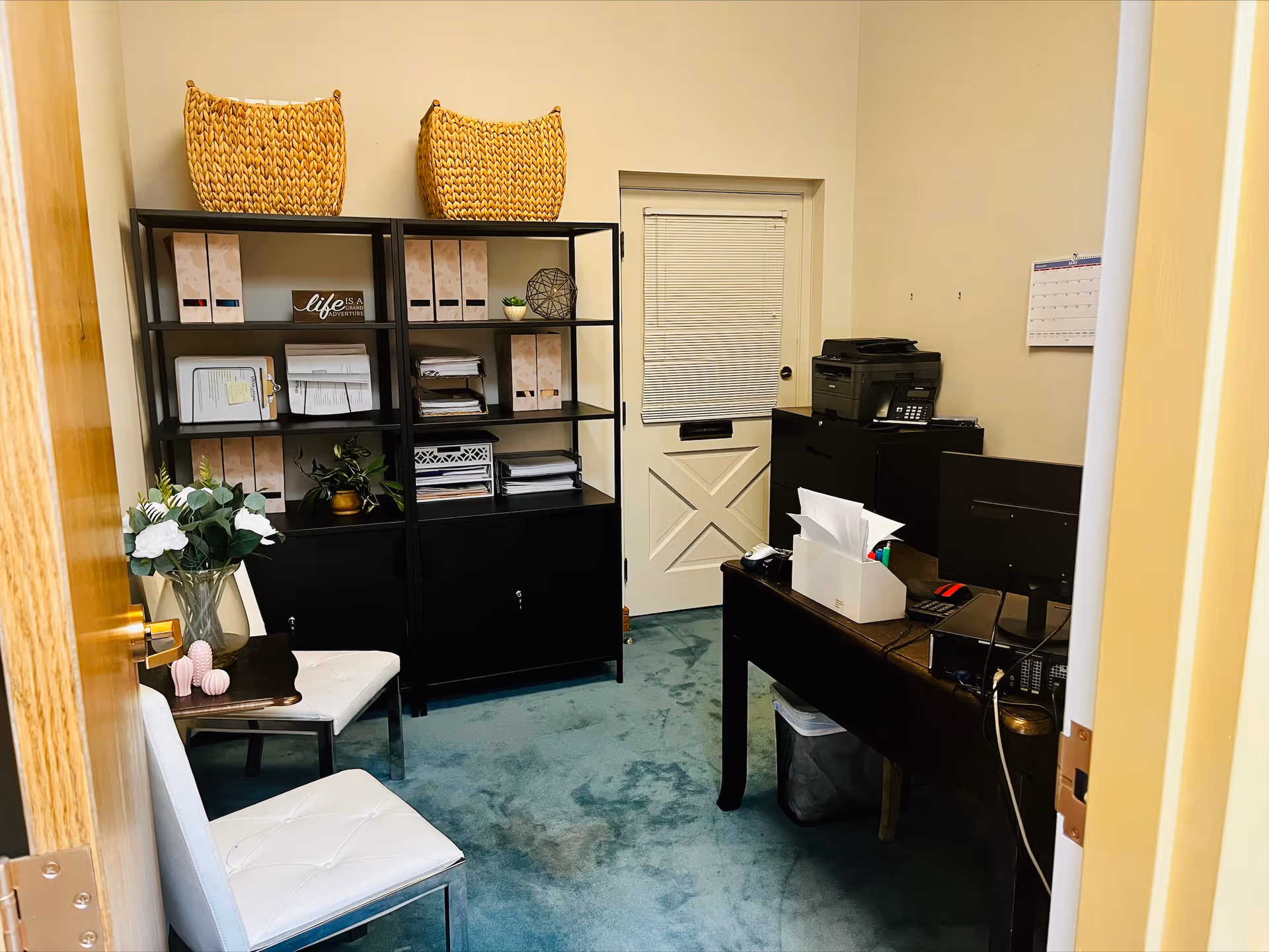 Interior office area with desk, computer, printer, shelves, and decorative baskets.