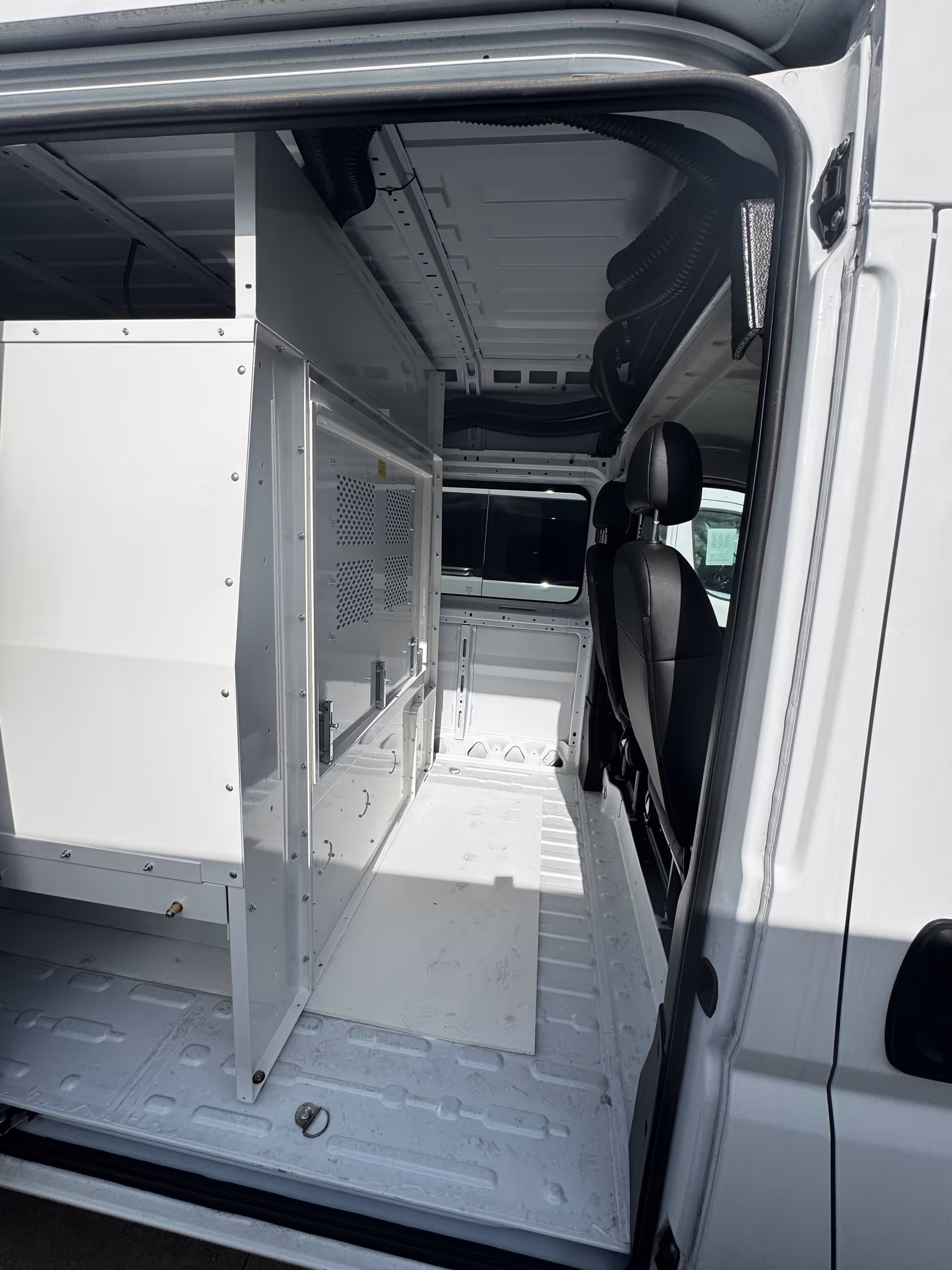 White van interior with metal storage shelves and a black driver's seat.
