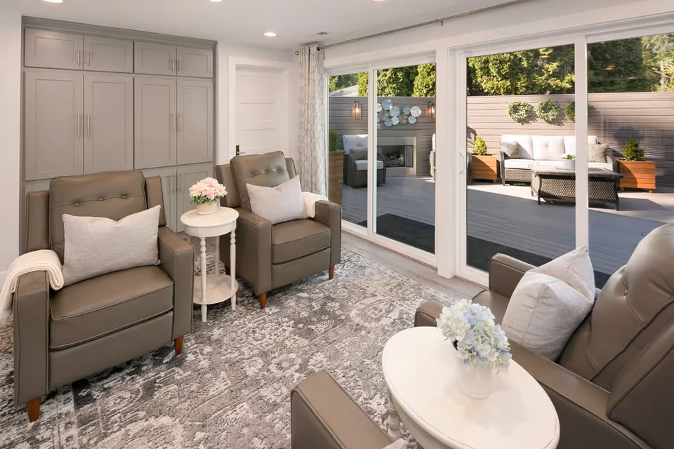 Modern living room with gray leather chairs and sliding glass doors to a patio.
