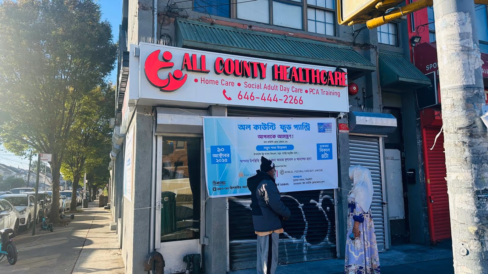 Storefront of All County Healthcare with two people standing beside a large banner.