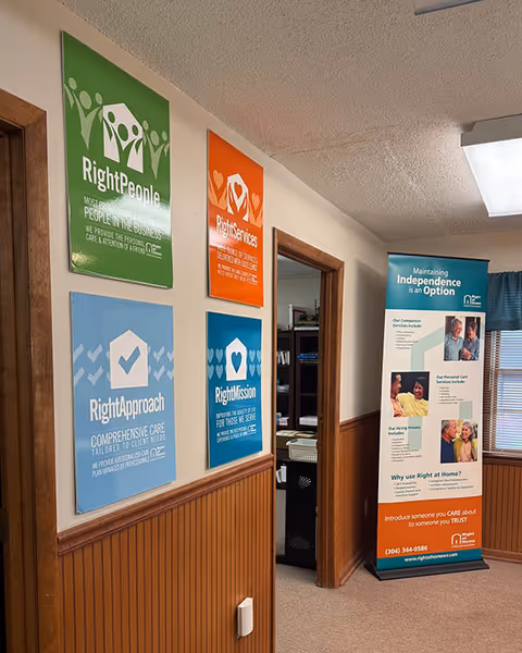 Corridor with colorful posters and a standing information banner inside a senior care facility.