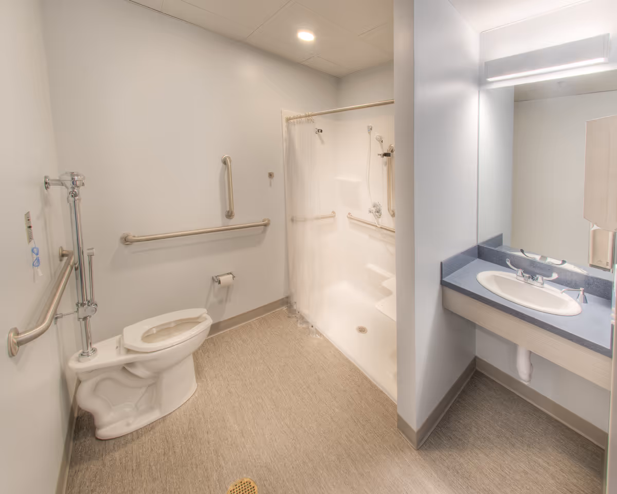 Accessible bathroom with grab bars, a shower, and a sink.