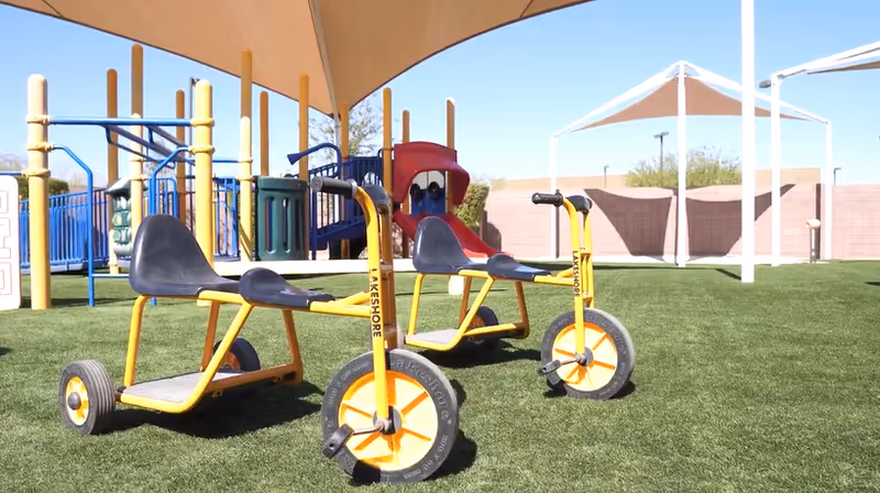 Outdoor playground area with yellow tricycles at UCP of Central Arizona.