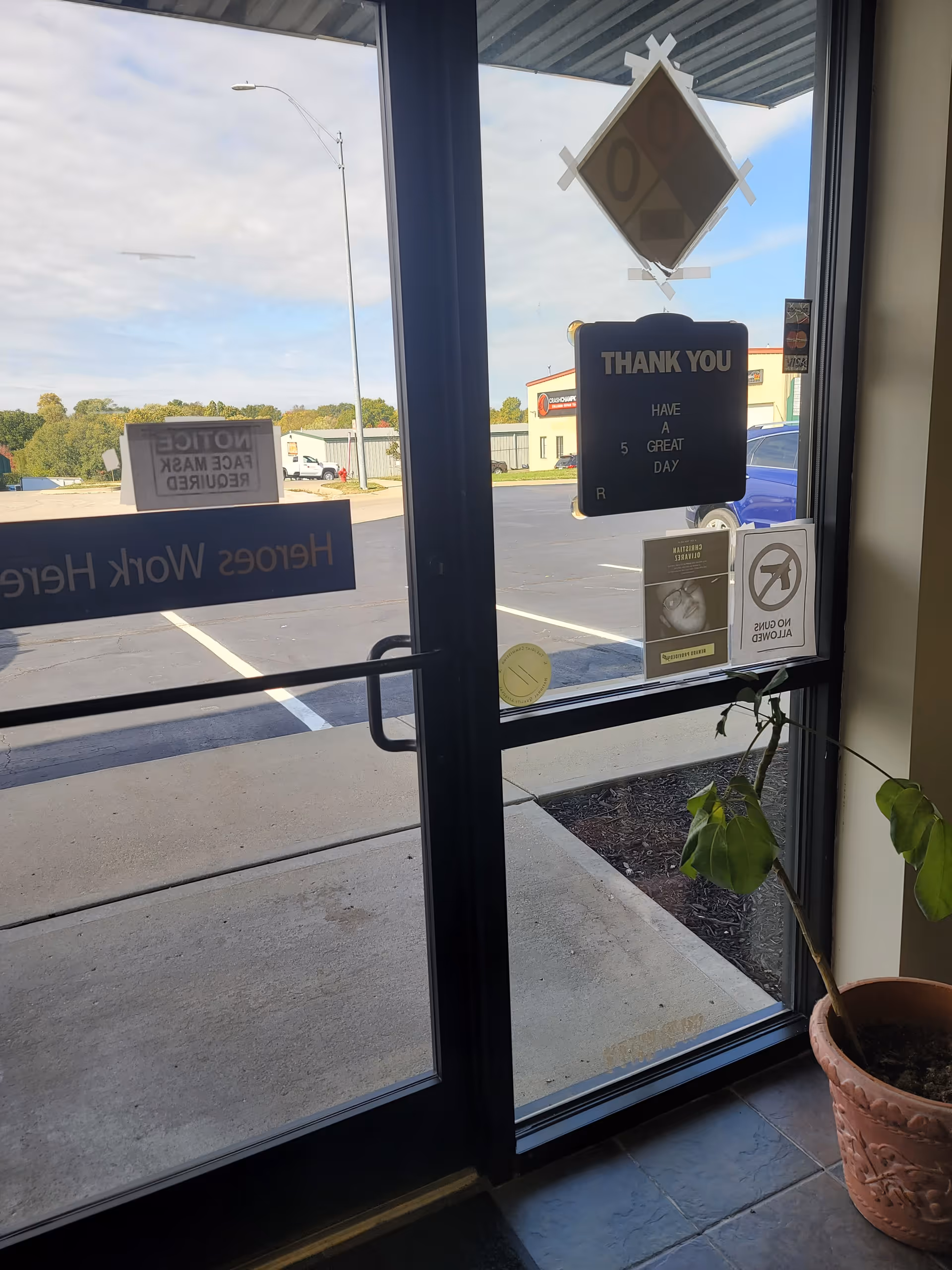 Interior entrance of a facility with glass doors, signs, and a potted plant.